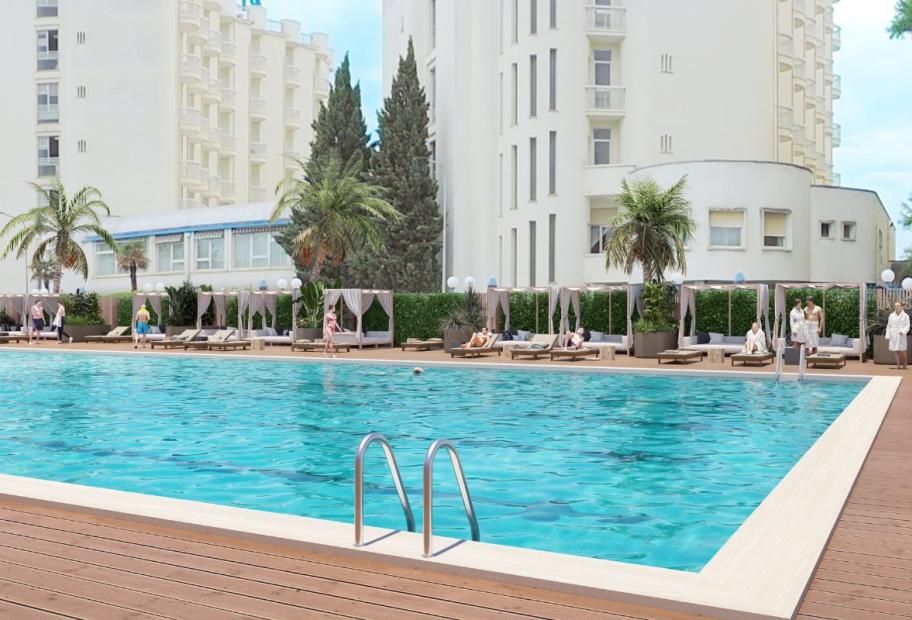 Outdoor pool surrounded by loungers and palm trees.